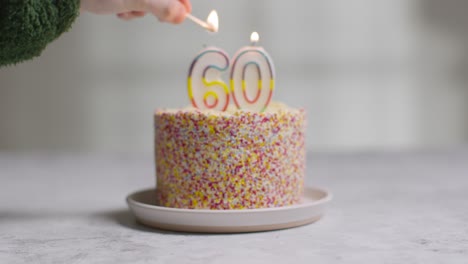 foto de estudio pastel de cumpleaños cubierto con adornos y velas celebrando el sexagésimo cumpleaños encendido