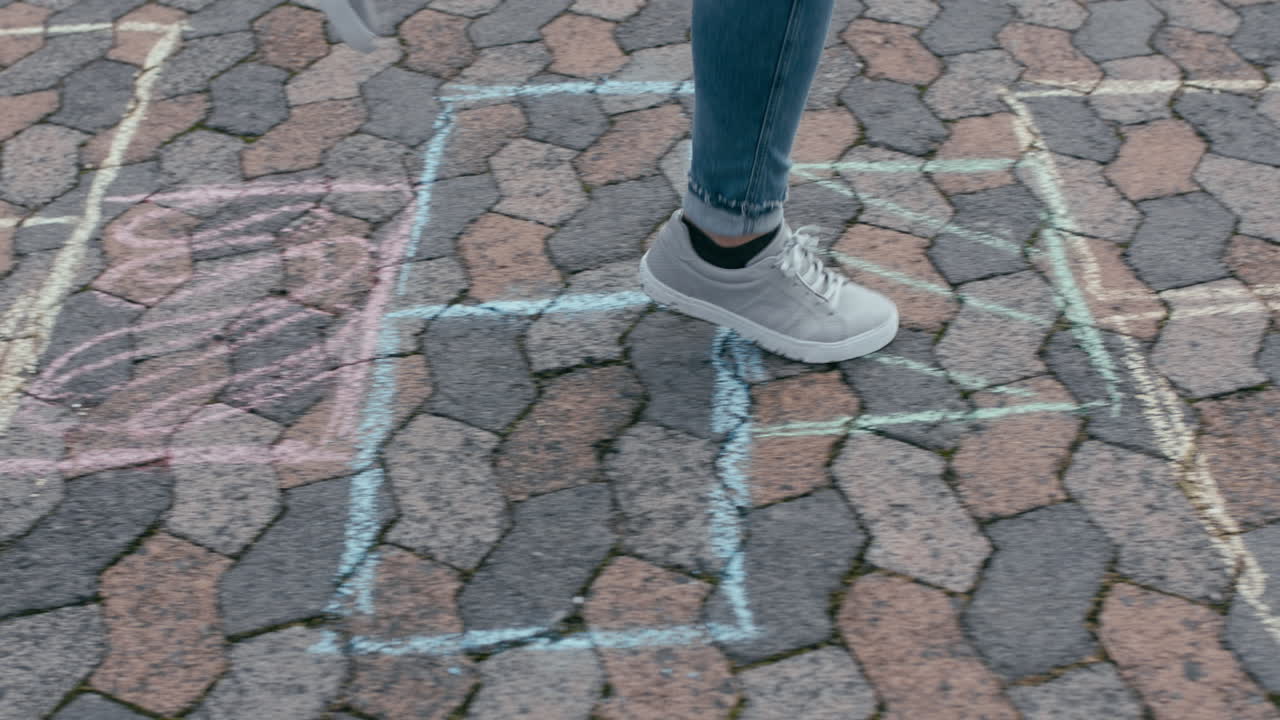 cerca de una adolescente jugando al juego de hopscotch saltando en cuadrados coloridos en el patio de recreo de la escuela divirtiéndose al aire libre