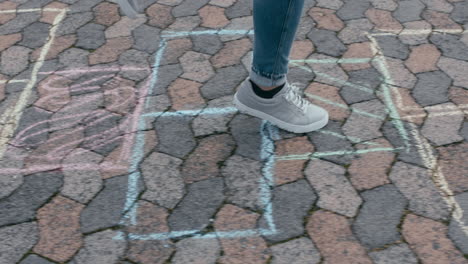 Nahaufnahme-Eines-Teenager-Mädchens,-Das-Himmel-Und-Hölle-Spielt,-Auf-Bunten-Plätzen-Auf-Dem-Schulhof-Springt-Und-Spaß-Im-Freien-Hat