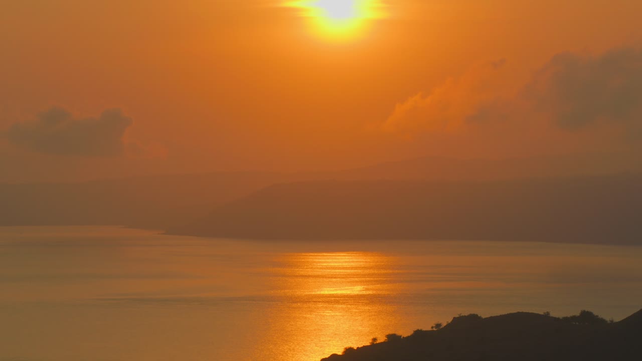 인도네시아의 코모도 국립공원 (komodo national park) 에 있는 파드 섬의 산악 해안에서 볼 수 있는 아름다운 해가 지거나 해가 뜨는 모습.