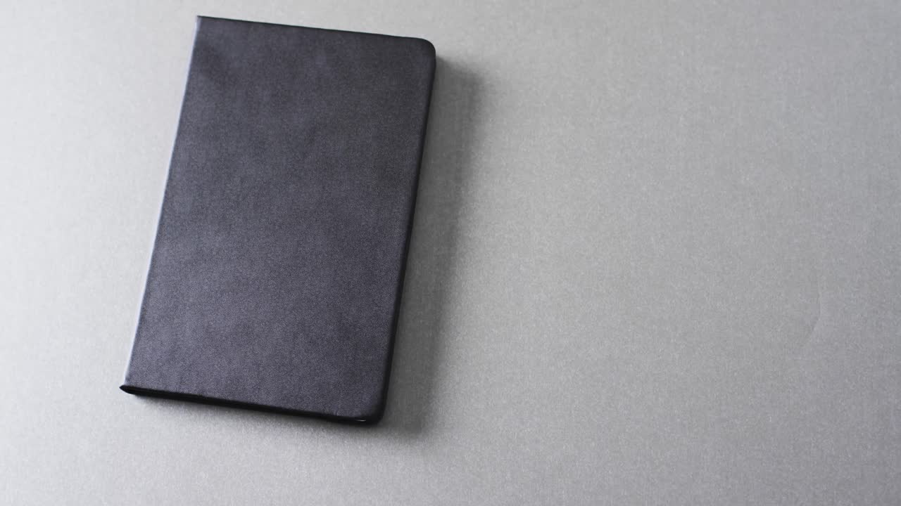 Close up of closed black book with copy space on gray background in slow motion