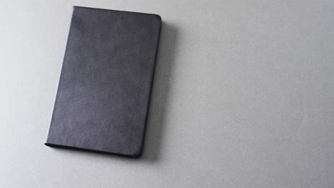 close up of closed black book with copy space on gray background in slow motion