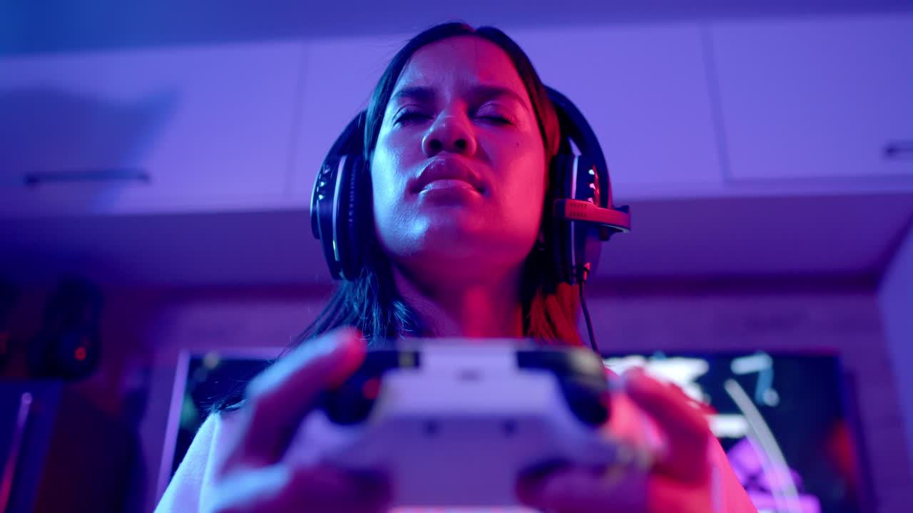 teenage girl wearing headset playing video game with controller, focusing intensely