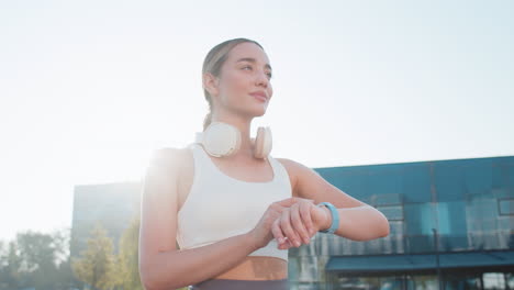 una joven corredora mira un dispositivo de reloj inteligente, una pulsera de ritmo cardíaco, un pulso spo2 en un parque de la ciudad.