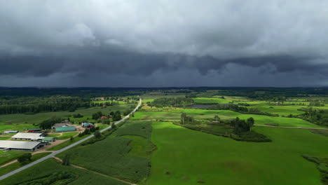 wide angle aerial shot of a green field at a countryside under cloudy day. dramatic cloudy sky adds depth to the scenic countryside panorama.
