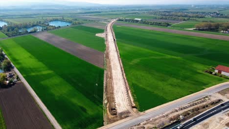 AERIAL---Railroad-construction-and-farmland,-Baden,-Austria,-wide-approach-shot