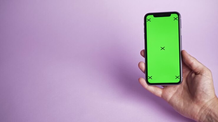 Telefono cellulare con schermo verde su sfondo viola, vista dall'alto.