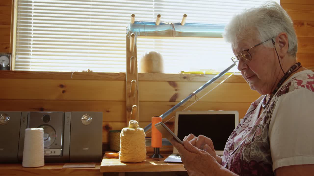 Vista laterale di una donna anziana caucasica che lavora su un tablet digitale e si siede a una scrivania in un laboratorio 4k.