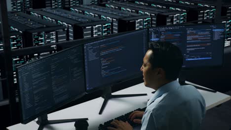 vista trasera de un hombre asiático cansado bostezando mientras trabajaba con un simulacro de varios monitores de computadora en el centro de datos