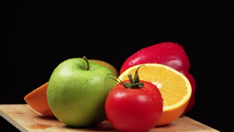 Colorful-fruits-and-vegetables-rotating-on-a-wooden-board-on-a-black-background