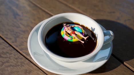 tiny man sunbathing in a coffee cup