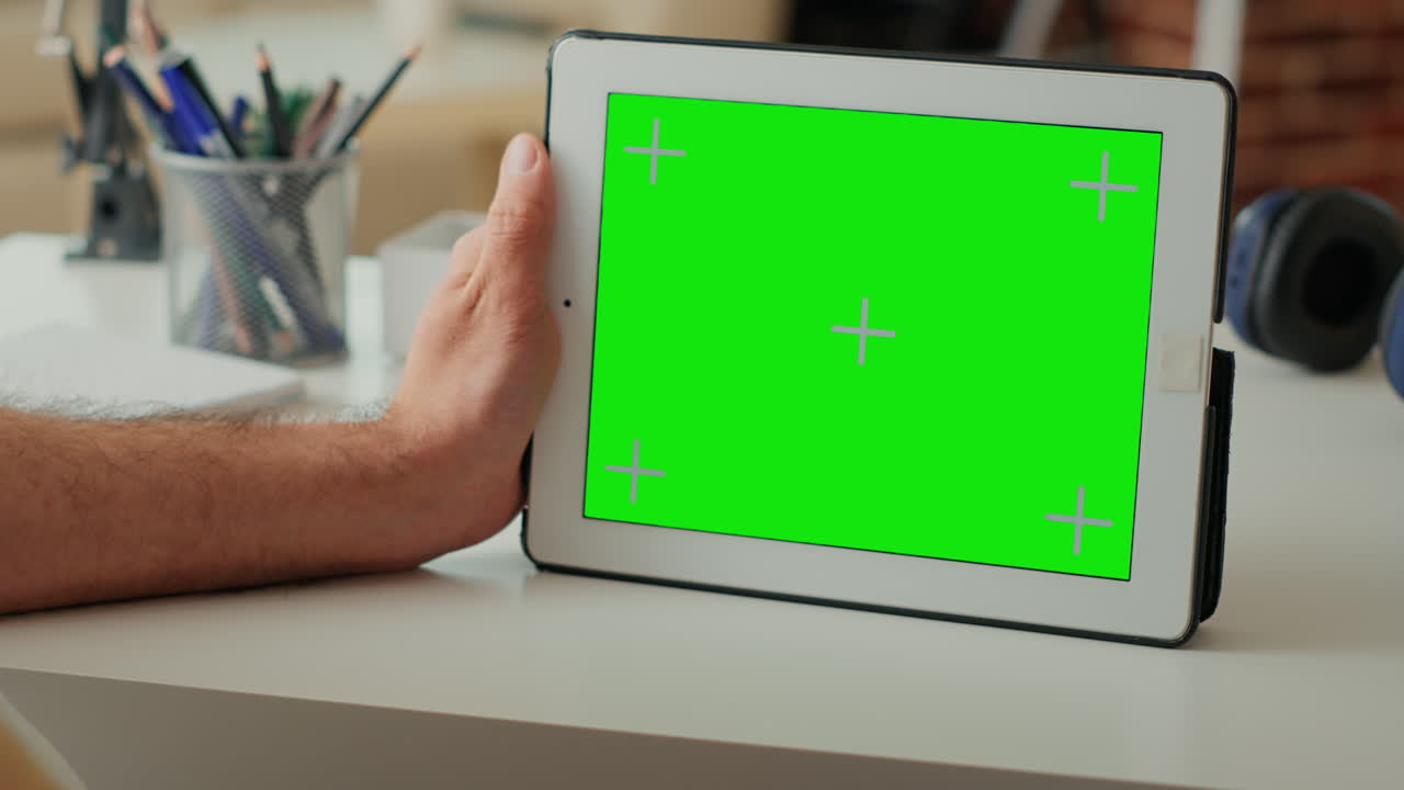 Male freelancer holding wireless device with horizontal greenscreen