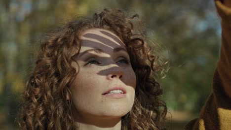 una mujer caucásica roja disfrutando de la luz del sol en el parque.