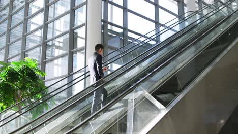 Young-businessman-on-an-escalator-in-a-modern-building