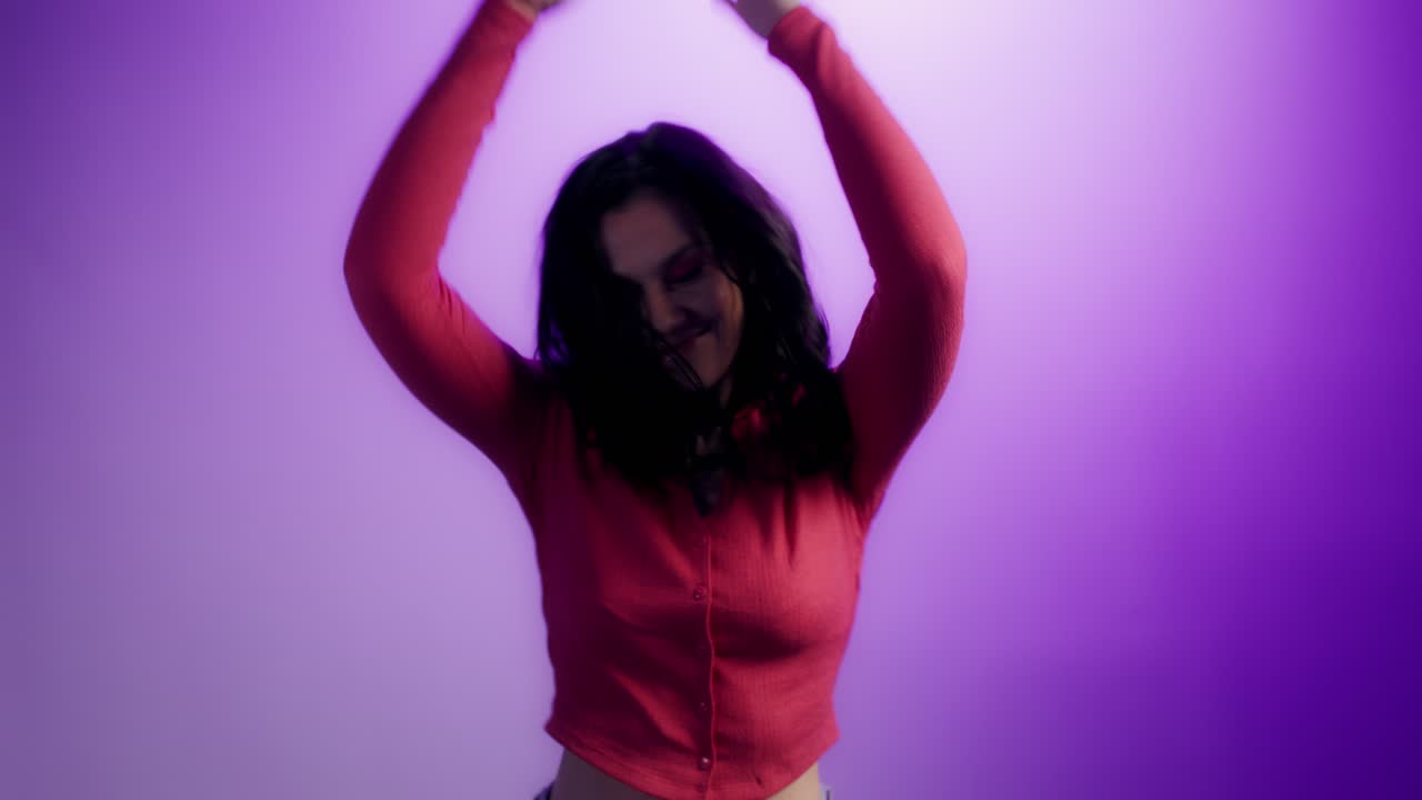 Woman Dancing in a Red Shirt Against a Purple Background