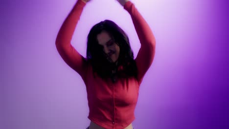 mujer bailando en una camisa roja contra un fondo púrpura