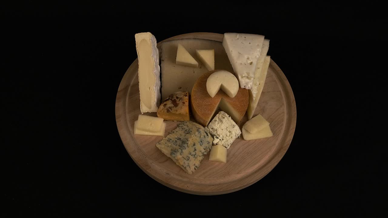 varios tipos de queso delicioso giran en la tabla de corte de madera