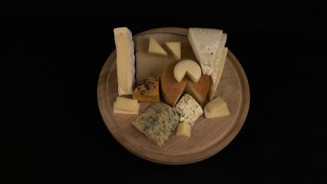 several kinds of delicious cheese rotate on wooden cutting board