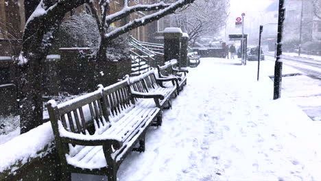 snowy london city scene with snowy benches at a bus stop