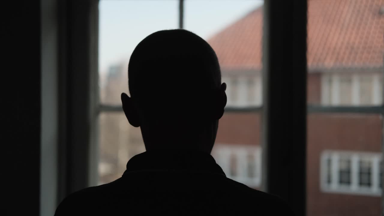 창문 앞에 서서 가발을 벗는 여성의 실루엣