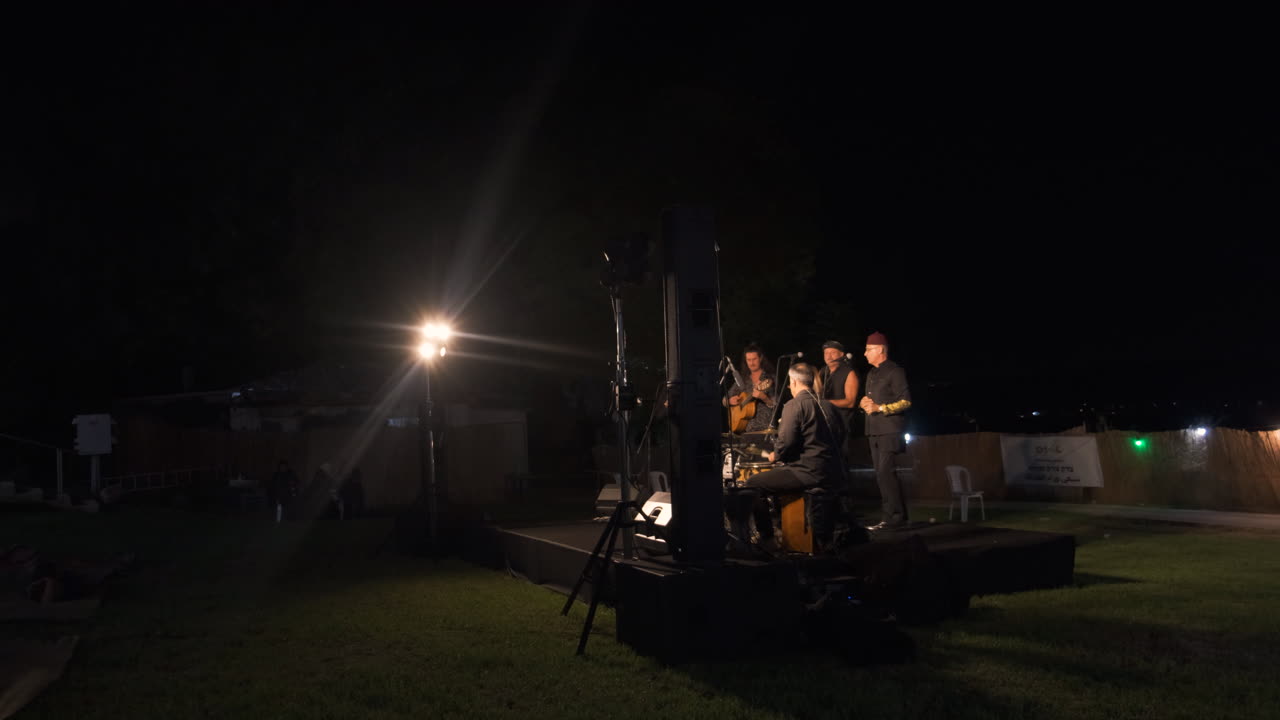 Band on stage, a beacon of light, their popular music kissing the night