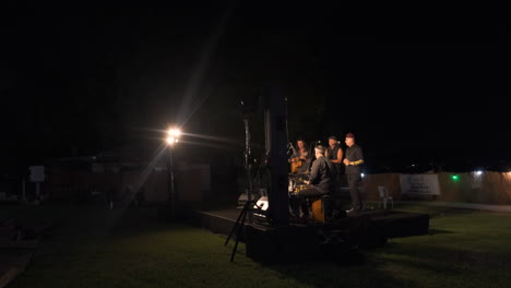 band on stage, a beacon of light, their popular music kissing the night