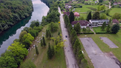 una vista aérea de un camión negro que avanza con el río y el patio de la tumba en una ciudad verde y exuberante