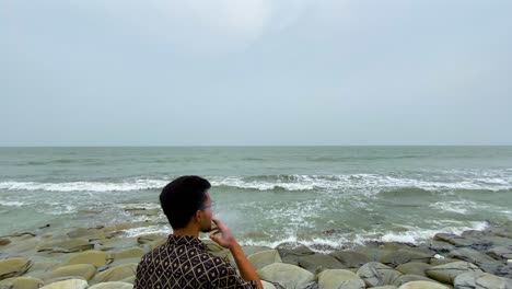 man smoking at the beach - medium shot