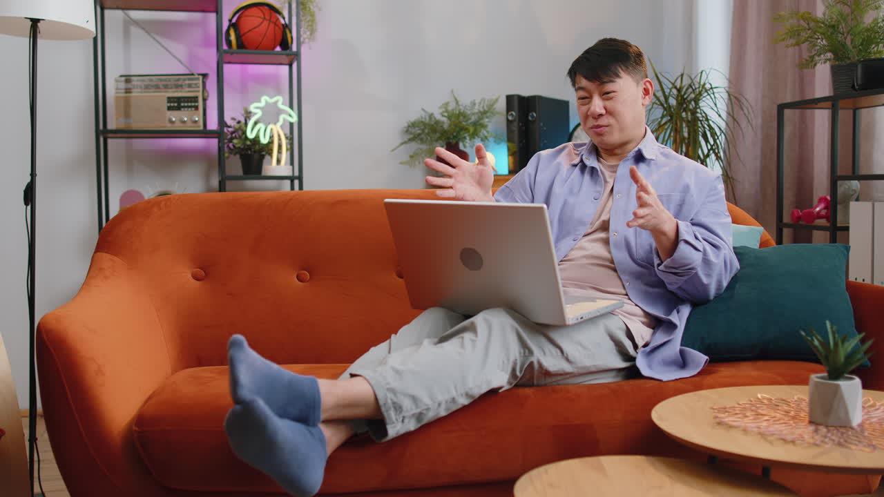 Man sitting on home couch looking at camera making video conference call with friends or family