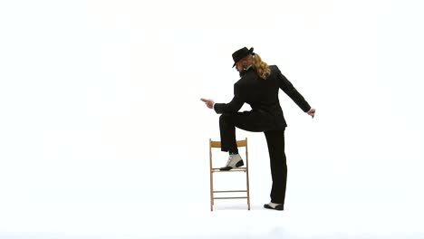 man in suit and fedora posing with chair on white background