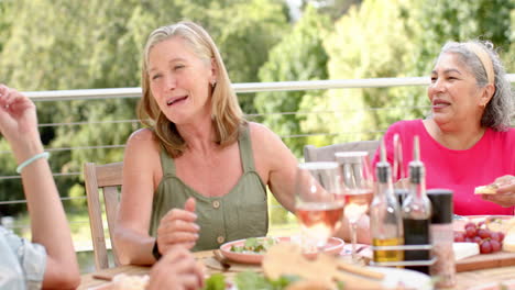 mujeres caucásicas y bi-raciales mayores disfrutan de una comida al aire libre soleada