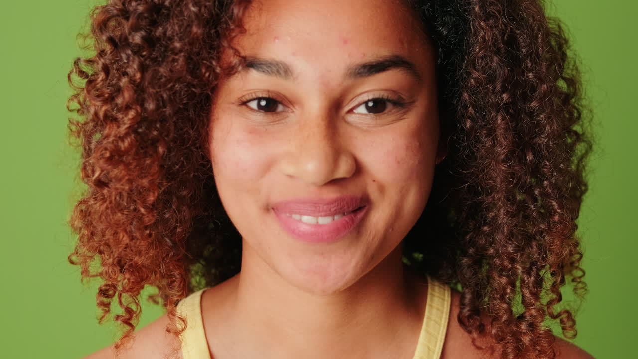 Primo piano di una giovane donna felice con i capelli ricci che sorride.