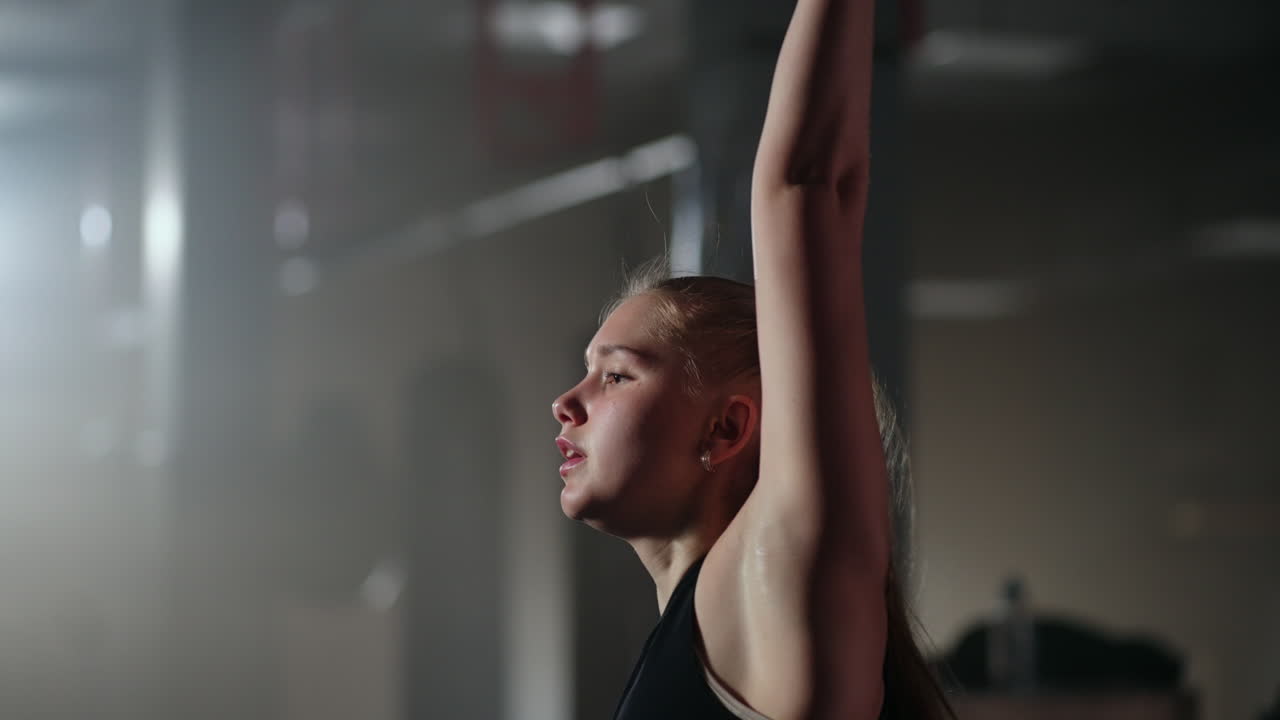 una mujer rubia está entrenando en el gimnasio levantando pesas en cámara lenta trabajando duro en el centro de fitness