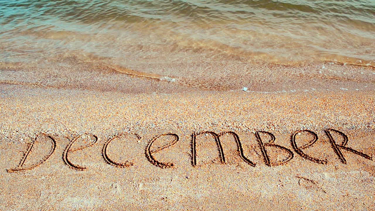 Scritta Dicembre sulla spiaggia. Servizio fotografico in spiaggia.