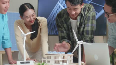 primer plano de un grupo de ingenieros asiáticos celebrando el final del ensamblaje del modelo de casas pequeñas con panel solar en la oficina
