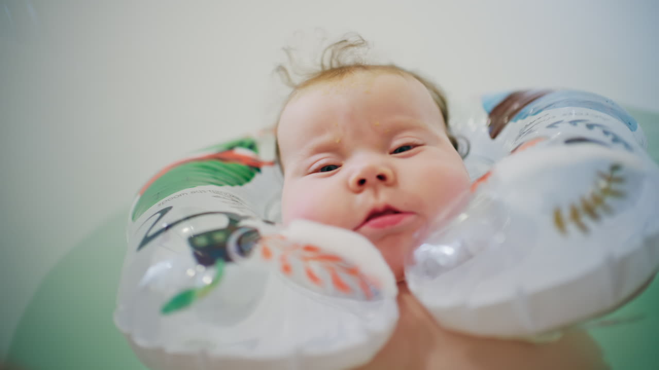 Close up of baby floating in bath support in bathtub with water reflections