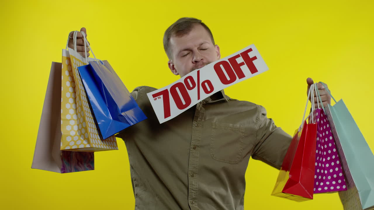 쇼핑백과 70%까지 할인된 글씨를 입에 넣은 남자가  놀랐다 - 블랙프라이데이
