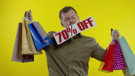 surprised man showing shopping bags and up to 70 percent off inscription in his mouth. black friday