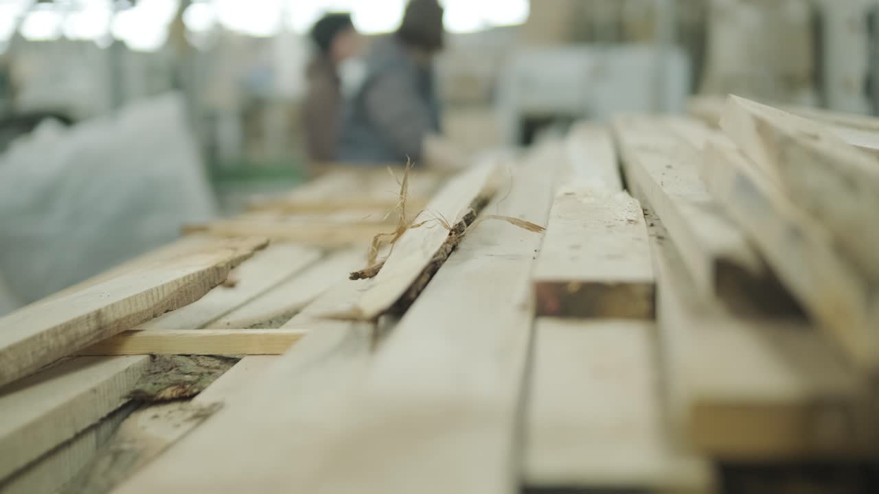 Assi di legno impilate con operai in uno sfondo sfocato di officina