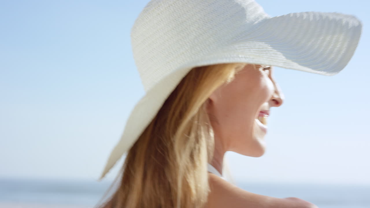 Close up of beautiful woman walking on beach looking back at camera smiling steadicam slow motion shot