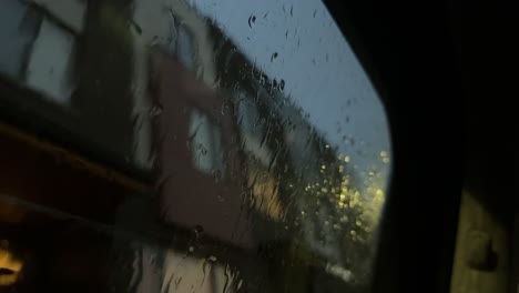 Close-up-of-car-window-interior-during-evening-rain---raindrops-on-glass-car
