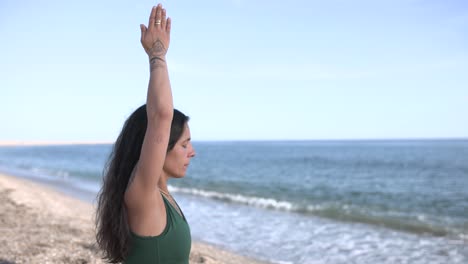 Woman practicing urdhva hastasana yoga pose on beach