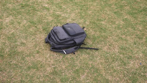 grey backpack thrown down on the grass