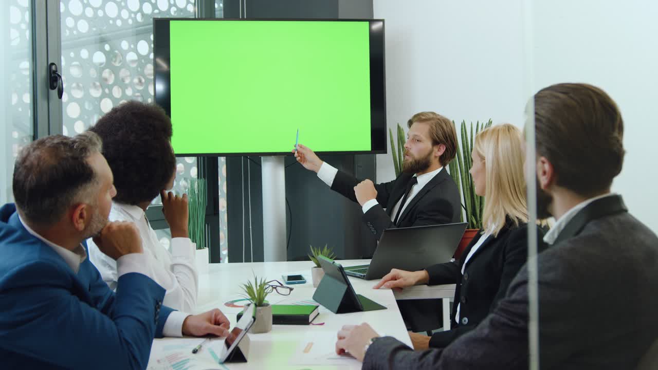 colegas multirraciales de buen aspecto, confiados, decididos que celebran una reunión en la sala de juntas usando una pizarra digital con pantalla verde de tecla cromática, de cerca