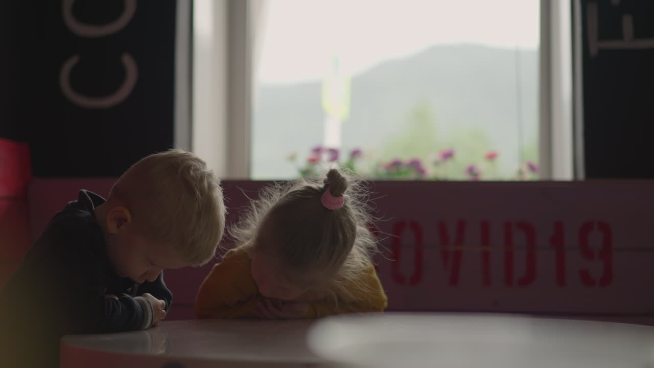 디저트 없이 남은 화가 난 소년과 소녀는 테이블 위에서 배 ⁇ 니다.