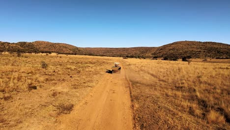 Imágenes-De-Drones-Siguiendo-A-Un-Tractor-Con-Remolque-En-Una-Granja-Remota