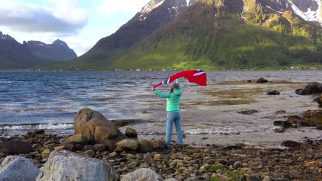 woman with a waving flag of norway on the background of nature