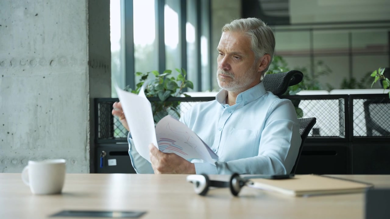 Mature Businessman Reviewing Financial Documents in Modern Office