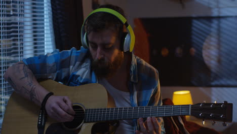 man playing acoustic guitar in bedroom
