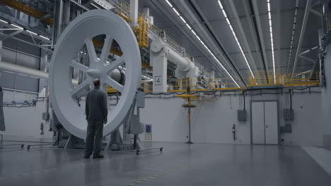 man observing massive industrial equipment in a high-tech facility